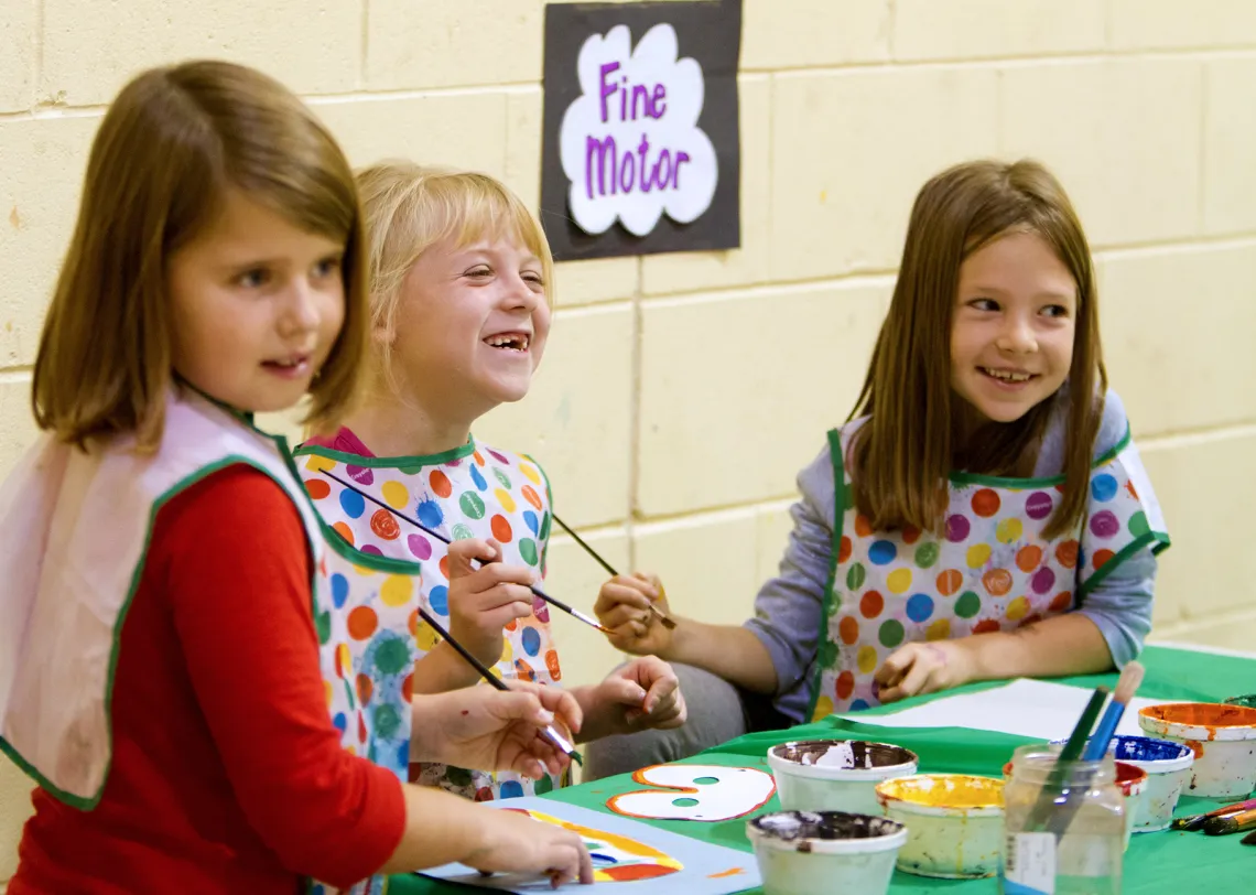School age girls painting with paint brushes