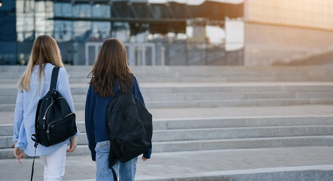 Two young people walking outside with backpacks 