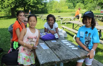 Group of female campers playing cards at picnic table