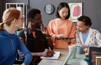 Four youth sitting inside at a table discussing career opportunities, smiling.