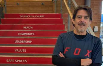 older adult male stands in front of red steps inside a building