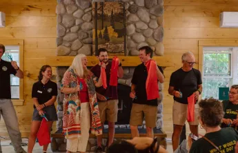 Group of people holding pieces of a red ribbon and scissors 