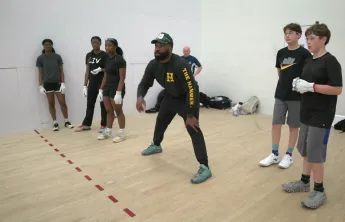 Coach showing youth how to play handball in a handball court