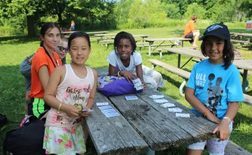 Group of female campers playing cards at picnic table