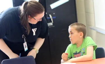 Educator bent over speaking with seated child