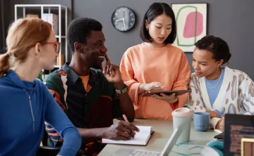 Four youth sitting inside at a table discussing career opportunities, smiling.