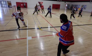 adults in gym playing floor hockey