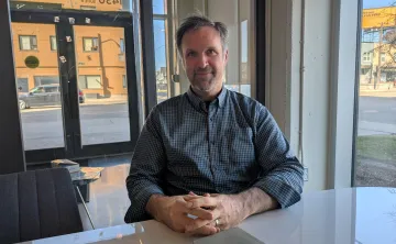 man sits with his hands crossed at a desk