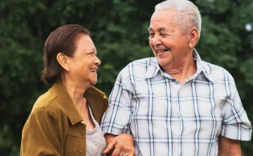 Two older individuals walking together and smiling