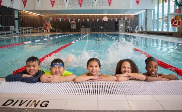 kids kicking water at side of pool and smiling