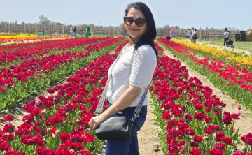 women stands in field of red tulips