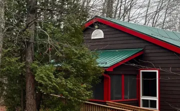 Brown cabins with forest green steel roofs and red trim