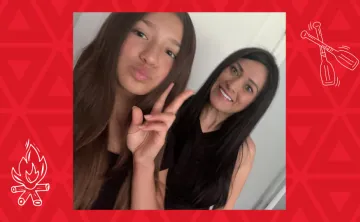 Girl holding peace sign with mother smiling