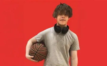 Teenage boy holding a basketball on a red background