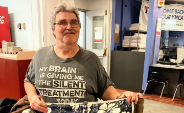 Older man in front of Y membership desk holding shorts 