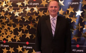 Older gentleman in a suit standing in front of a wall with stars