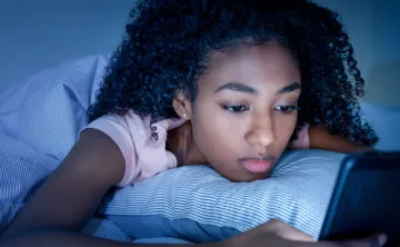 young girl looking at phone in dark room, frowning