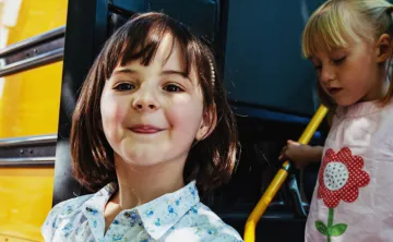 young girls get off yellow bus to summer camp