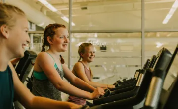 three girls on treadmills smiling