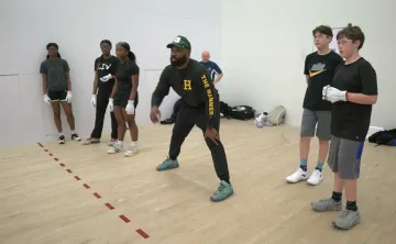 Coach showing youth how to play handball in a handball court
