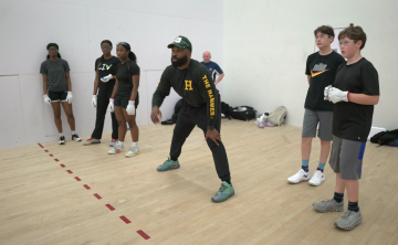 Coach showing youth how to play handball in a handball court